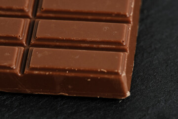 Bar milk chocolate on a black slate.