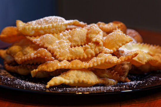 Frappe or chiacchiere with castagnole on a plate full of sugar. Typical Italian sweets of the carnival celebration. Cooked in all households and pastry shops. Also known as bugie lies