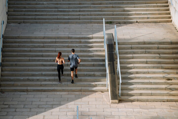 Sportive couple during workout stair running outside. Fitness active lifestyle athletic people exercising cardio climbing staircase.