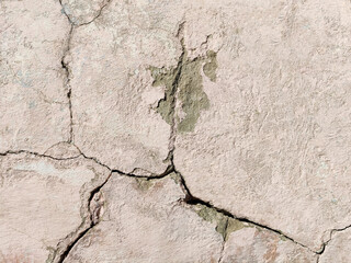 Obraz premium The wall of an old building with crumbling plaster and many winding, deep cracks. Copy space. Selective focus.