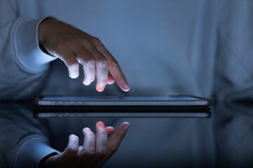 female hands typing on a tablet in a dark office room, close-up