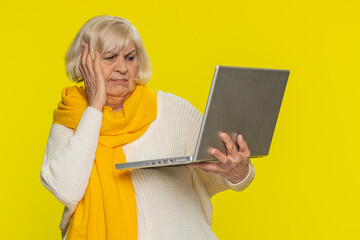 Displeased senior woman use laptop notebook typing browsing working loses becoming surprised by...