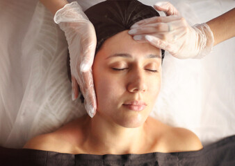 Fototapeta na wymiar Crop massage therapist massaging face of client