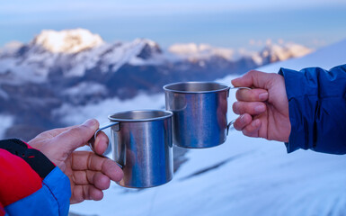 Young woman holding a metal hot tea cup during sunset time from the Mera Peak high camp with snowy...