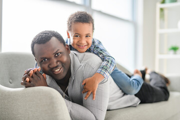 Obraz premium American father with little boy at home lay on sofa