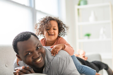 Obraz premium American father with little girl at home lay on sofa