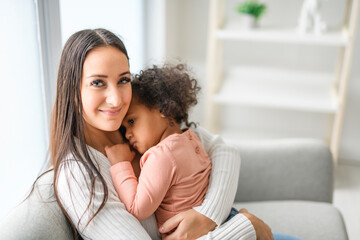 Mother with little daughter at home sofa consoling