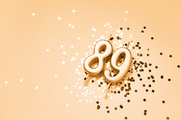 89 years celebration festive background made with golden candles in the form of number Eighty-nine lying on sparkles. Universal holiday banner with copy space.