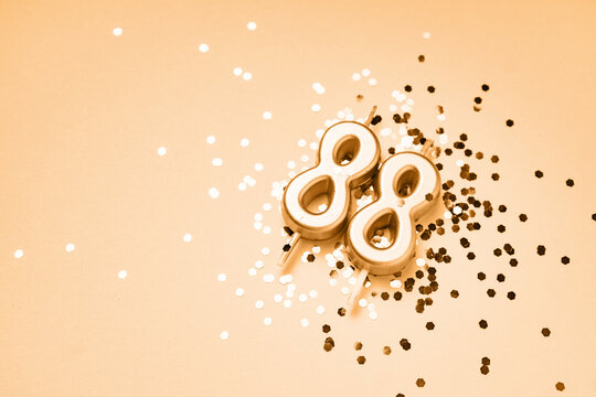 88 years celebration festive background made with golden candles in the form of number Eighty-eight lying on sparkles. Universal holiday banner with copy space.
