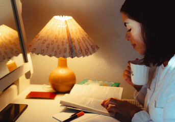 Beautiful latin woman consulting travel guides at the desk of the hotel where she is staying to...