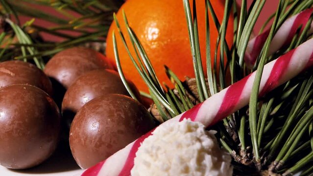 Chocolate and coconut Christmas balls - candies are spinning on the table. Tangerines. Pine needles for decoration. Video clips. Soft selective focus. Artificially created grain for the picture