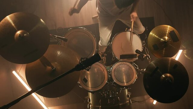 Top view male drummer hits the drums. Drummer rehearsing on drums in a dark studio. Music or song recording