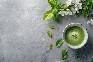 Matcha green tea in a bowl with spring flowers on a stone background. Traditional japanese matcha tea ceremony. Healthy organic drink concept. Springtime composition