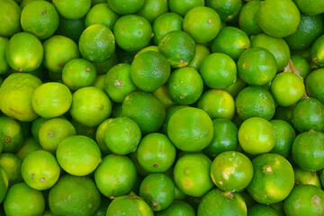 Fresh green ripe lime fruits on retail market stall display, close up view. 