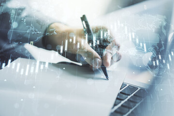 Multi exposure of abstract creative financial chart with world map and with hand writing in notebook on background with laptop, research and analytics concept