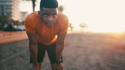 Black man, fitness and rest in sunset after exercise, outdoor cardio training or workout for recovery. Tired African male person, athlete or runner in break, breathing or sport by the city coast - Powered by Adobe