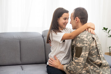 Young man in military uniform with his wife on sofa at home