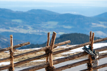 Holzzaun mit Schuhen und verschneiter Landschaft im Hintergrund