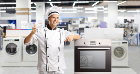 Male chef gesturing thumbs up next to a stove