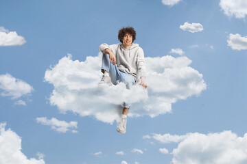 Obraz premium Guy with curly hair sitting on a cloud and smiling