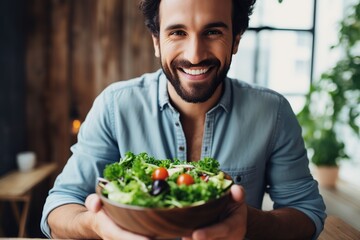 Beautiful man eating healthy salad in the kitchen