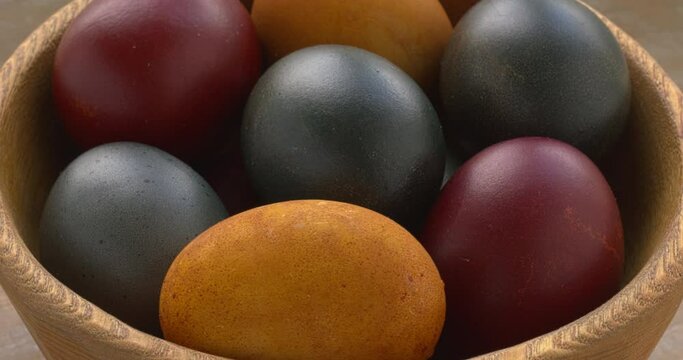Eggs colored in organic dyes (onion skin, turmeric, red cabbage). Easter concept. Zooming in while rotating.