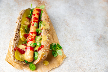 Hot Dog sausage on bun, tomato sauce, pickled cucumber, greens lettuce leaf takeaway food tasty fresh eating cooking appetizer meal food snack on the table