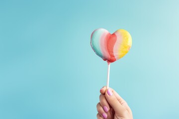 Colorful lollipop in shape of heart on blue background