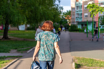 an elderly woman walks down the street in a blouse in summer