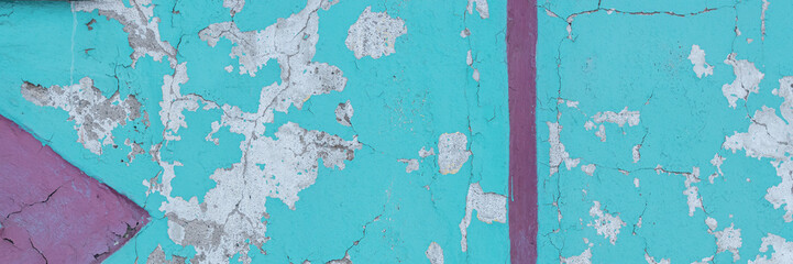 Peeling paint on the wall. Panorama of a concrete wall with old cracked flaking paint. Weathered rough painted surface with patterns of cracks and peeling. Panoramic texture for background and design.