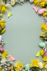 Spring flowers ans easter eggs border on green background with copy space. Easter greeting card template