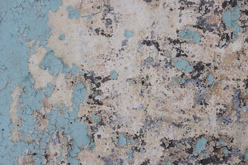 Peeling paint on the wall. Old concrete wall with cracked flaking paint. Weathered rough painted surface with patterns of cracks and peeling. Grunge texture for background and design. High resolution.