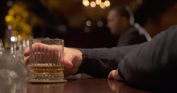 Adult man enjoying glass of whiskey or brandy at the bar in the evening. Slow motion
