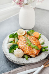 Salmon steak with vegetables cauliflower, broccoli, carrots and green beans. Salad of arugula and vegetables with salmon