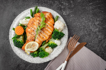 Salmon steak with vegetables cauliflower, broccoli, carrots and green beans. Salad of arugula and vegetables with salmon.
