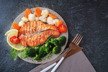 Salmon steak with vegetables cauliflower, broccoli, carrots and green beans. Salad of arugula and...