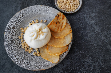 burrata is served with roasted caramelized pear and pine nuts. Top view, flat lay.
