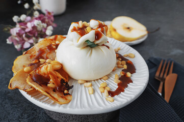 burrata is served with roasted caramelized pear and pine nuts. Close-up
