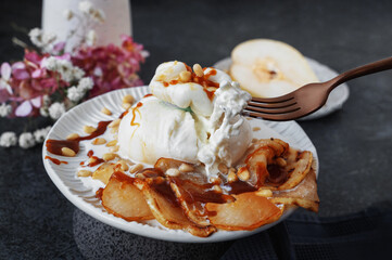 Use a fork and knife to cut the burrata. Burrata cheese served with baked caramelized pear and pine nuts. Close-up.