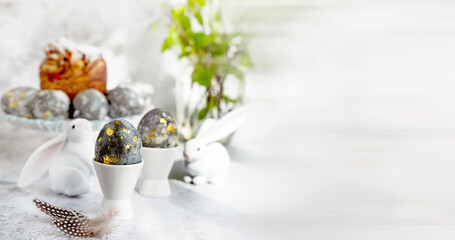 Banner. Easter eggs with gold pattern. A plate with Easter eggs and bunny figures. The concept of home comfort in the bright holiday of Easter.
