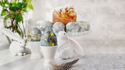 Easter eggs with gold pattern. A plate with Easter eggs and bunny figures. The concept of home comfort in the bright holiday of Easter