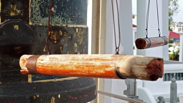 The pair of a hanging wooden log - beam used for strike at bell in a Buddhist temple