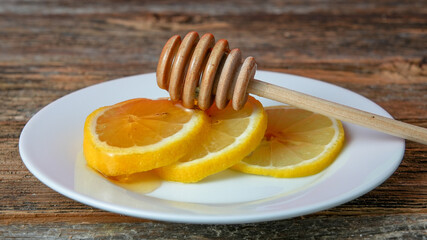 Wooden spoon for honey on lemons on white plate on wooden rustic table