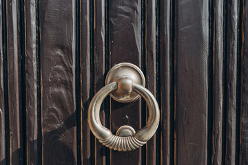 Antique brass door knocker in the shape, door element with metal knob. A old door handle on a vintage wooden black door - Powered by Adobe