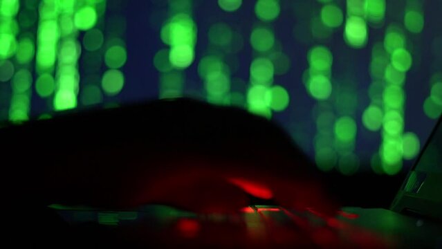 Hands of a cybercriminal working with a computer keyboard. On a green background 