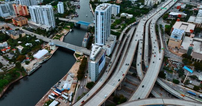 Rising above the ramified highway going along the narrow river in downtown. View of Miami, Florida, USA from top.