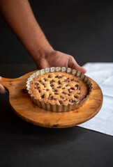 Pizza-cookie ready to be served. It is as big as a personal pan pizza. this huge chocolate chip cookie is made in a pastry pan. chef is proudly showing his pizzookie