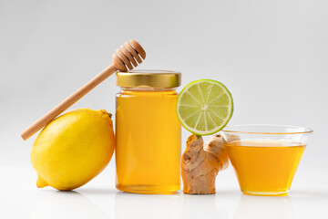 Composition of honey in a jar, lemon, lime, ginger isolated. - Powered by Adobe