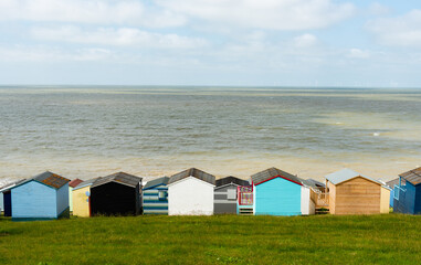 Fototapeta na wymiar Colorful holiday beach huts homes facing the calm blue sea.