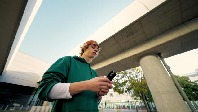 Focused hipster texting smartphone at city closeup